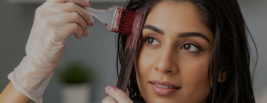 Woman getting professional red hair dye applied with a tint brush at home