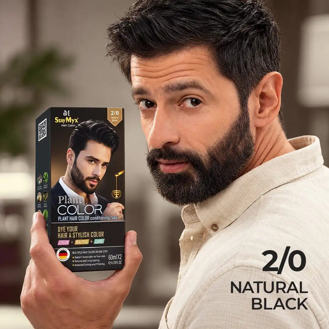 Man with natural black hair and beard holding StayMyx 2/0 Natural Black hair dye box for men's hair coloring.