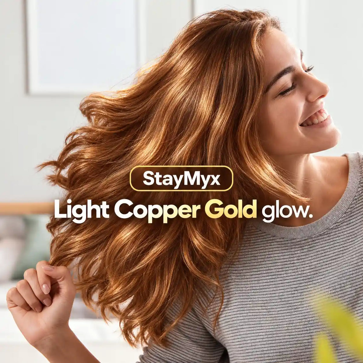 Smiling woman with long, glossy light copper gold hair showcasing StayMyx hair color results with warm golden copper tones, vibrant shine, and soft-looking waves.