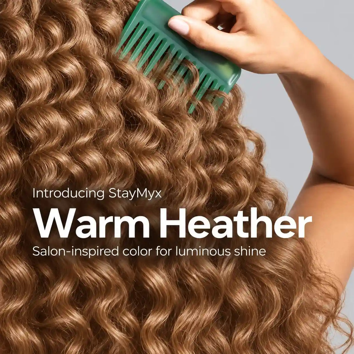 Close-up of glossy, warm heather-colored curly hair being styled with a green comb, showcasing StayMyx salon-inspired hair color and luminous shine.