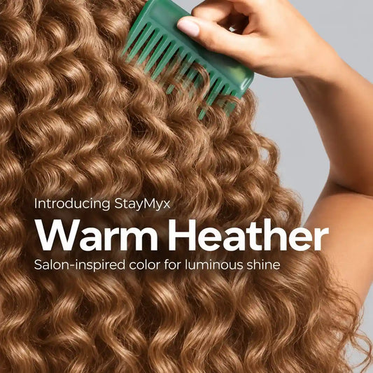 Close-up of glossy, warm heather-colored curly hair being styled with a green comb, showcasing StayMyx salon-inspired hair color and luminous shine.